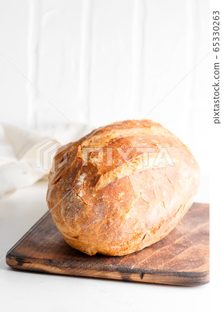 Homemade freshy baked bread on a wooden board and light grey marble table decorated textile towel. Homemade freshy baked bread on a wooden board and light grey marble table decorated textile towel. 65330263