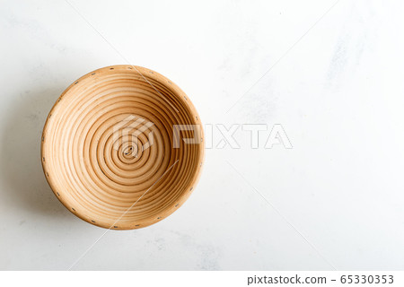 Handmade wicker basket for homemade freshly baked pastry on a light grey marble background. 65330353