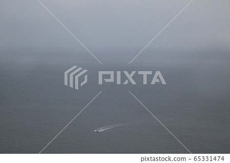 A small fishing boat rushing through the thick fog on its way back to its home port 65331474