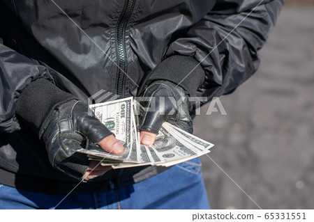 money in the hands of a bandit, a robber who counts the loot 65331551