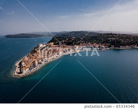Aerial view on Piran town with old lighthouse, ancient buildings with red roofs, the port of Piran with boats and Adriatic sea in southwestern Slovenia Aerial view on Piran town with old lighthouse, ancient buildings with red roofs, the port of Piran with boats and Adriatic sea in southwestern Slovenia 65334346