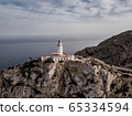 Aerial view on beautiful white Lighthouse of Cap de Formentor in the Coast of North Mallorca, Spain Balearic Islands at sunset. Wide view of wild rocky cliffs. 65334594