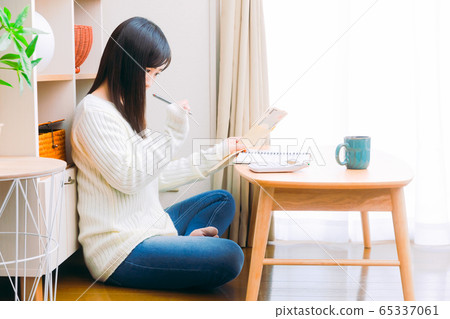 一個用手寫的家庭帳簿，生計管理和副本空間計算現金的女人 65337061