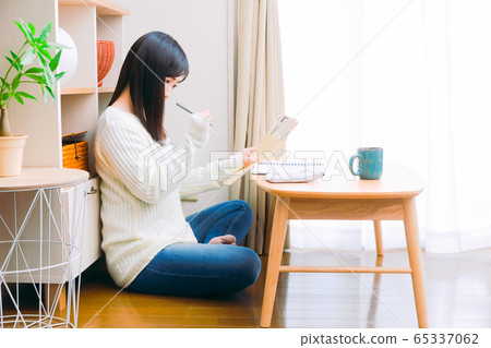 一個用手寫的家庭帳簿，生計管理和副本空間計算現金的女人 65337062