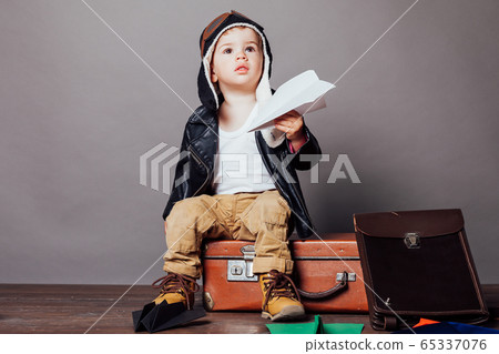 Boy in pilot's suit plays with paper planes Boy in pilot's suit plays with paper planes 65337076