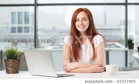 Portrait of a beautiful girl working at a computer at a Desk in the office. on the phone 65337405