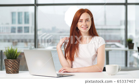 Portrait of a beautiful girl working at a computer at a Desk in the office. on the phone 65337407