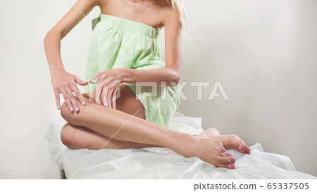 young woman enjoys her well-groomed smooth legs after epilation 65337505