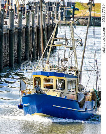 A small fishing boat enters the harbour of Busum in North Frisia in Germany. A small fishing boat enters the harbour of Busum in North Frisia in Germany. 65337759