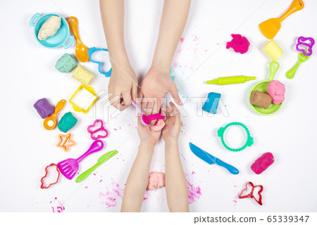 Two little girls play with modeling clay on white background Two little girls play with modeling clay on white background 65339347
