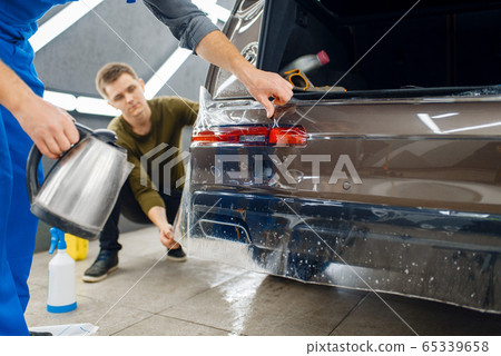 Specialists applies car protection film on bumper 65339658