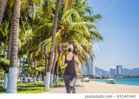 Woman runner wearing medical mask. Running in the park. Coronavirus pandemic Covid-19. Sport, Active Woman runner wearing medical mask. Running in the park. Coronavirus pandemic Covid-19. Sport, Active 65340340
