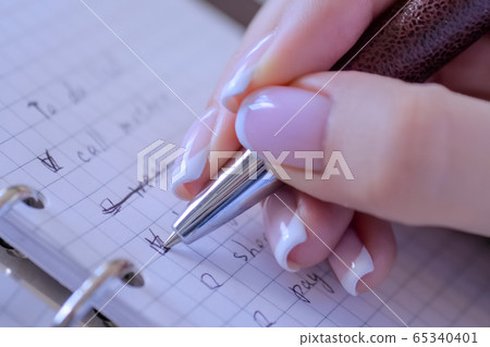 Close up view - woman putting mark on check boxes of to do list in notebook Close up view - woman putting mark on check boxes of to do list in notebook 65340401