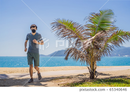 Man runner wearing medical mask. Running in the city against the backdrop of the city. Coronavirus 65340646