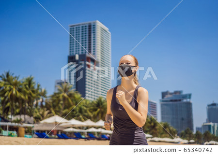 Woman runner wearing medical mask. Running in the city against the backdrop of the city. Coronavirus 65340742
