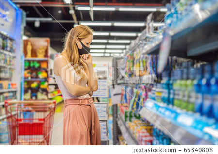 Alarmed female wears medical mask against coronavirus while purchase of household chemicals in Alarmed female wears medical mask against coronavirus while purchase of household chemicals in 65340808