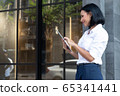 Half figure portrait smart businesswoman smiling, use tablet in front of office building in downtown 65341441