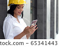Half figure portrait smart successful engineer woman use smartphone in front of building in downtown 65341443