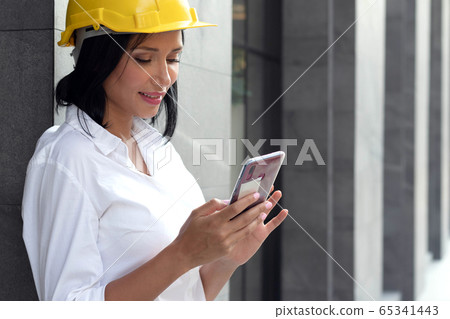 Half figure portrait smart successful engineer woman use smartphone in front of building in downtown Half figure portrait smart successful engineer woman use smartphone in front of building in downtown 65341443