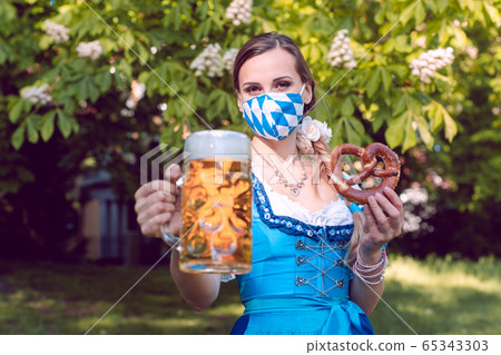Bavarian woman toasting with beer during covid-19 65343303