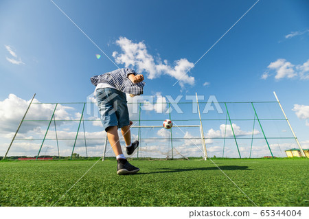 Boy kicking a penalty at goal playing with his father on a green grass. 65344004