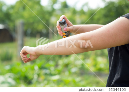 Young woman spraying mosquito, insect repellent in the forrest, insect protection, helathcare concept 65344103