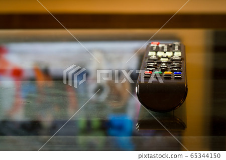 TV television remote on the glass table, ready for watching film or serial TV television remote on the glass table, ready for watching film or serial 65344150