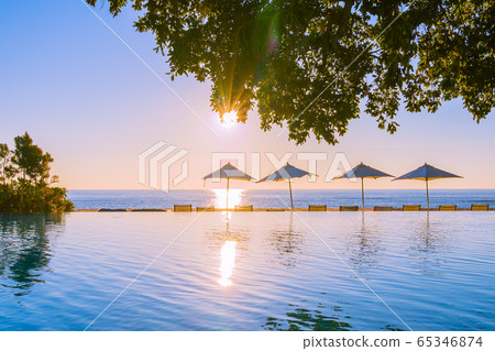 Beautiful tropical outdoor beach sea ocean with umbrella and chiar around outdoor swimming pool at sunset or sunrise time Beautiful tropical outdoor beach sea ocean with umbrella and chiar around outdoor swimming pool at sunset or sunrise time 65346874