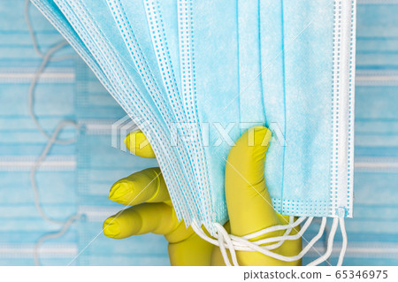 Nurse holding group blue medical surgical face masks in yellow protective glove in hand. Medicinal concept, quarantine, pandemic outbreak Nurse holding group blue medical surgical face masks in yellow protective glove in hand. Medicinal concept, quarantine, pandemic outbreak 65346975