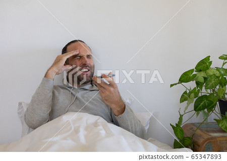 Sick Caucasian man self isolating and social distancing in quarantine lockdown during coronavirus co 65347893