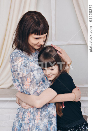 Warming and relaxing near fireplace. Mother and daughter hugging. Concept of family , motherhood, interior, home, childhood, mother's day, children's day 65350275