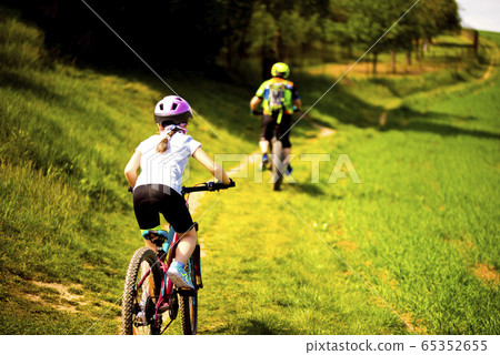9 years girl going in bicycle across the fields in the sunny day 65352655