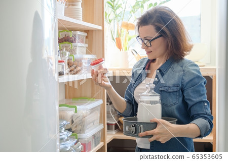 Interior of wooden pantry with products for cooking. Adult woman taking kitchenware and food 65353605