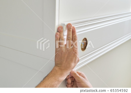 Closeup of gluing wooden white painted plank panel on wall, closeup, carpentry, woodwork, profession, people Closeup of gluing wooden white painted plank panel on wall, closeup, carpentry, woodwork, profession, people 65354592