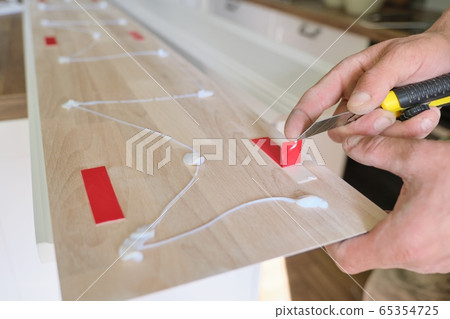 Carpenter male using construction glue when working with wooden white painted board, closeup, carpentry, woodwork, profession, people 65354725