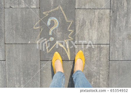 Abstract question mark drawn in crayons on gray asphalt with women legs in yellow shoes 65354932