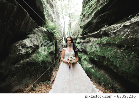 Portrait of stunning bride with long hair posing with great bouquet 65355230