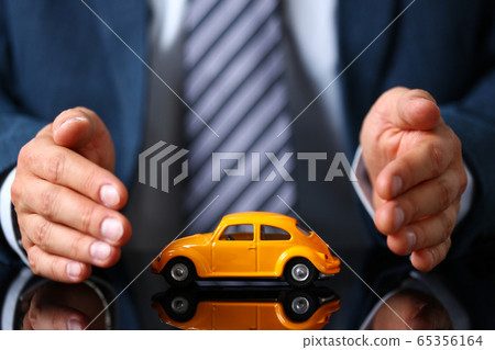 Male arm in suit and tie cover yellow toy car 65356164