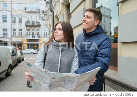 Outdoor portrait of young couple travelers in spring city, young man and woman reading city map Outdoor portrait of young couple travelers in spring city, young man and woman reading city map 65356502
