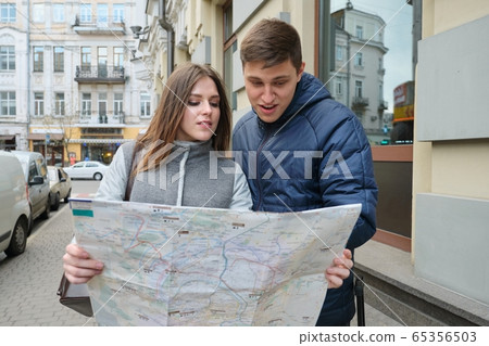 Outdoor portrait of young couple travelers in spring city, young man and woman reading city map Outdoor portrait of young couple travelers in spring city, young man and woman reading city map 65356503