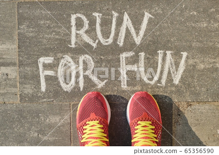 Run for fun, written on gray sidewalk with woman legs in sneakers, top view 65356590