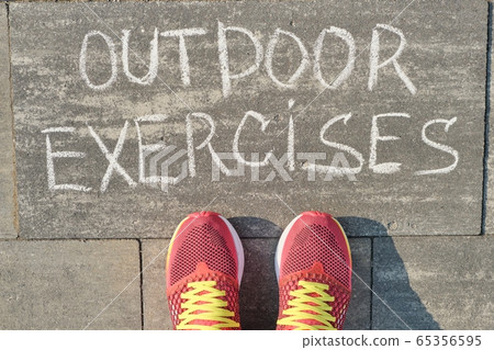 Outdoor exercises, written on gray sidewalk with woman legs in sneakers, top view 65356595