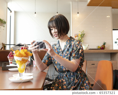 A woman taking a picture of a parfait with a smartphone A woman taking a picture of a parfait with a smartphone 65357321
