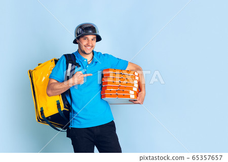 Contacless delivery service during quarantine. Man delivers food and shopping bags during insulation. Emotions of deliveryman isolated on blue background. 65357657