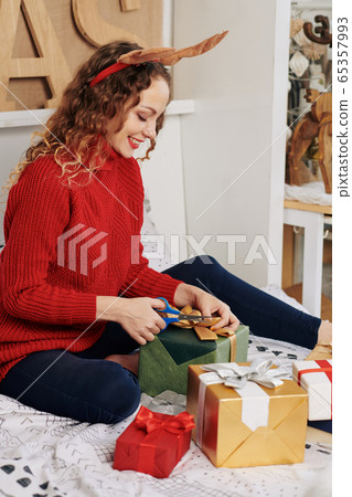 Cheerful woman wrapping Christmas gifts 65357993