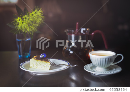 Teatime with slice of basque burnt cheesecake and cup of tea on table. 65358564