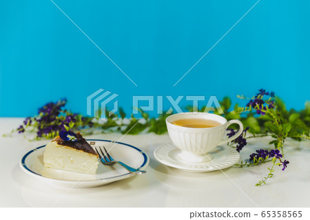 Teatime with slice of basque burnt cheesecake and cup of tea on table. 65358565