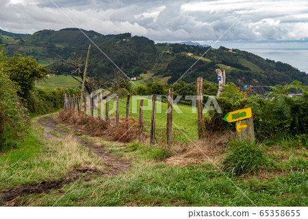 Hiking route leading to Deba, with pointers to the town in Basque Country, Spain. Camino de Santiago on a cloudy day 65358655