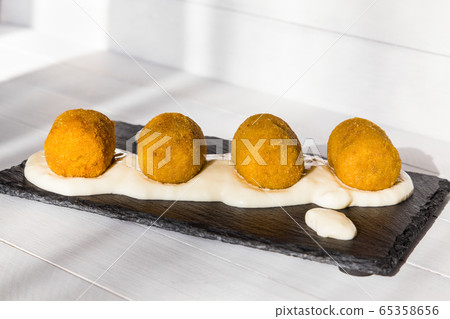 Fried vegetable croquettes with white sauce on black stone plate on wooden background. Unhealthy food. Side view 65358656