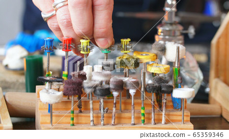 close-Up of the jeweler's hand selects the nozzle for polishing the jewelry. Close-up of jewelry polishing tips. close-Up of the jeweler's hand selects the nozzle for polishing the jewelry. Close-up of jewelry polishing tips. 65359346